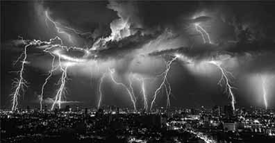 Black and white photo: lightning illuminates the city skyline, creating a dramatic contrast between light and darkness